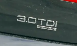 Napis "3.0 TDI quattro" na ciemnym lakierze samochodu. Informuje o pojemności silnika 3.0 litra i napędzie quattro.