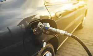 Tankowanie auta gazem. Złoty promień słońca odbija się od lakieru, gdy pistolet LPG jest włożony do wlewu paliwa. Sprawdzamy aktualną cenę LPG.