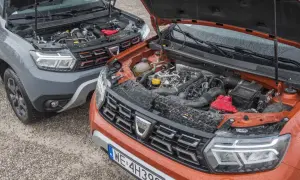 Dwa silniki Dacia Duster, szary i pomarańczowy, z otwartymi maskami. Który wybierzesz: diesel czy benzyna?