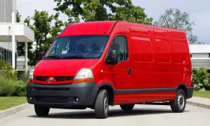 Czerwony Renault Master 2, gotowy do pracy, stoi na tle zieleni i nowoczesnego budynku.
