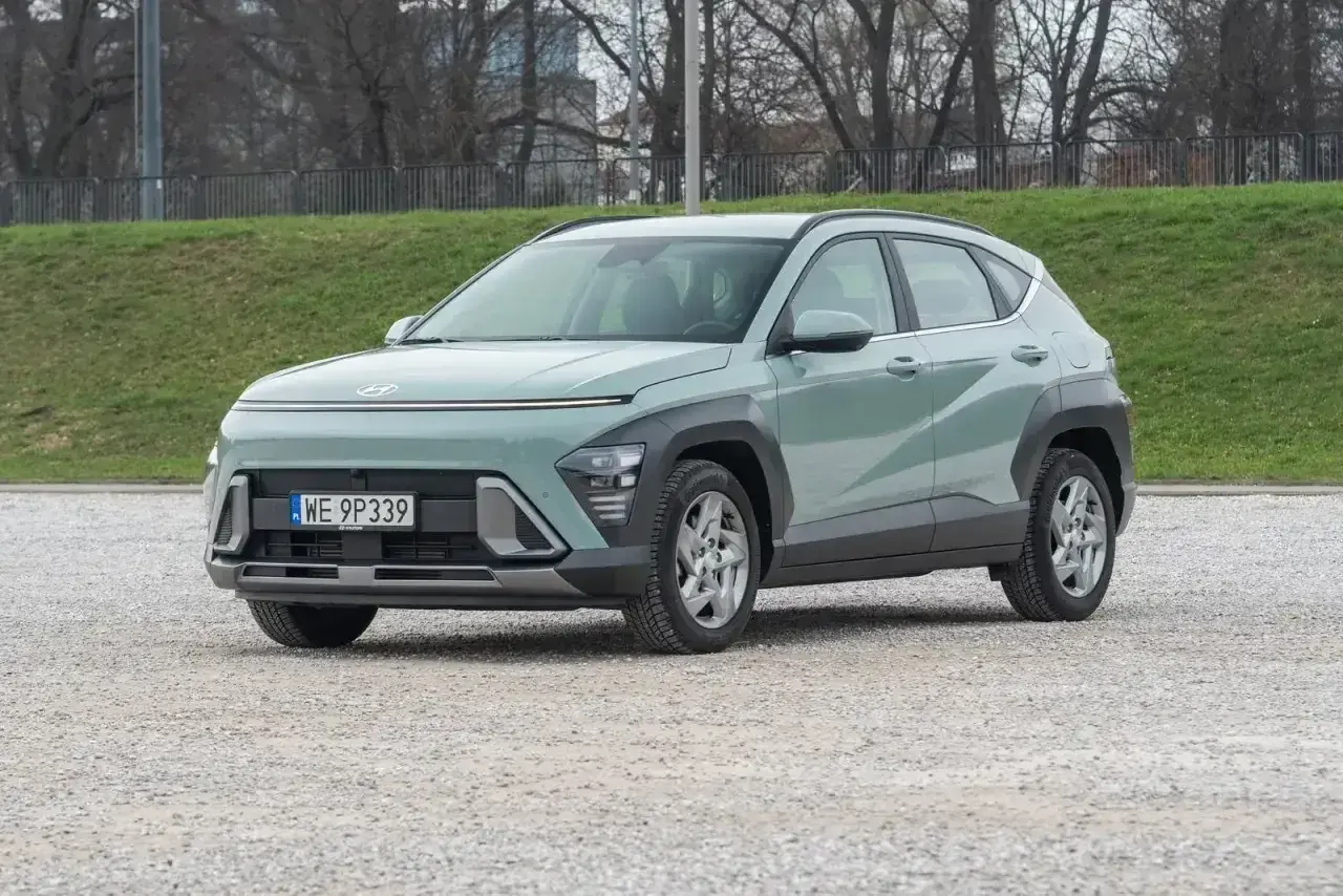 Nowy Hyundai Kona 2025 w kolorze miętowym prezentuje się nowocześnie na tle zieleni i drzew.