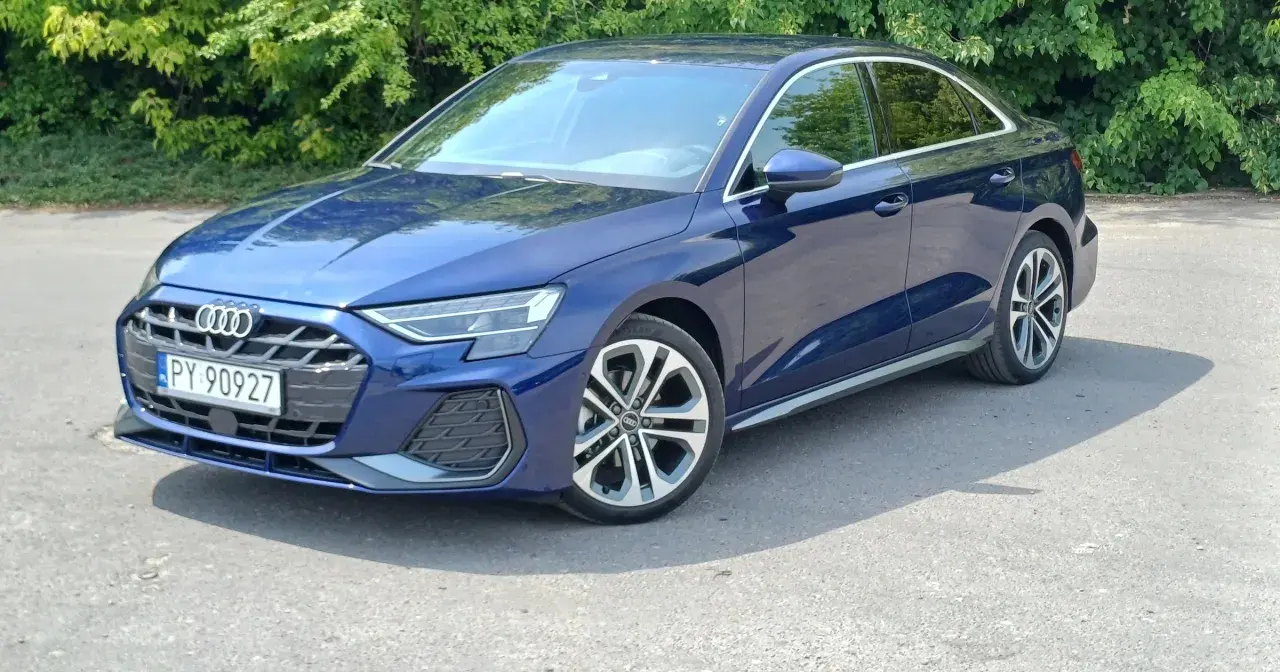 Elegancki, granatowy Audi A3 2025 sedan na tle zieleni.