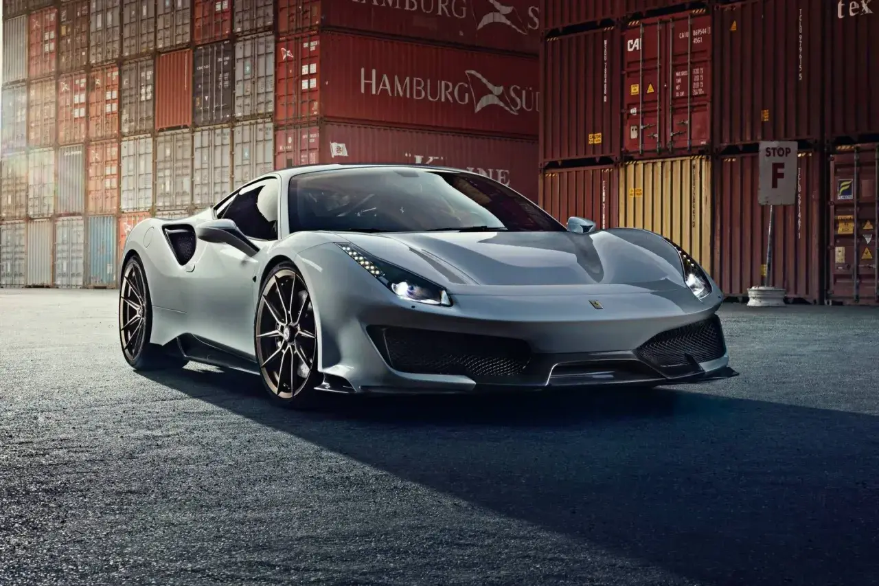 Srebrne Ferrari 488 Pista błyszczy na tle kontenerów portowych.