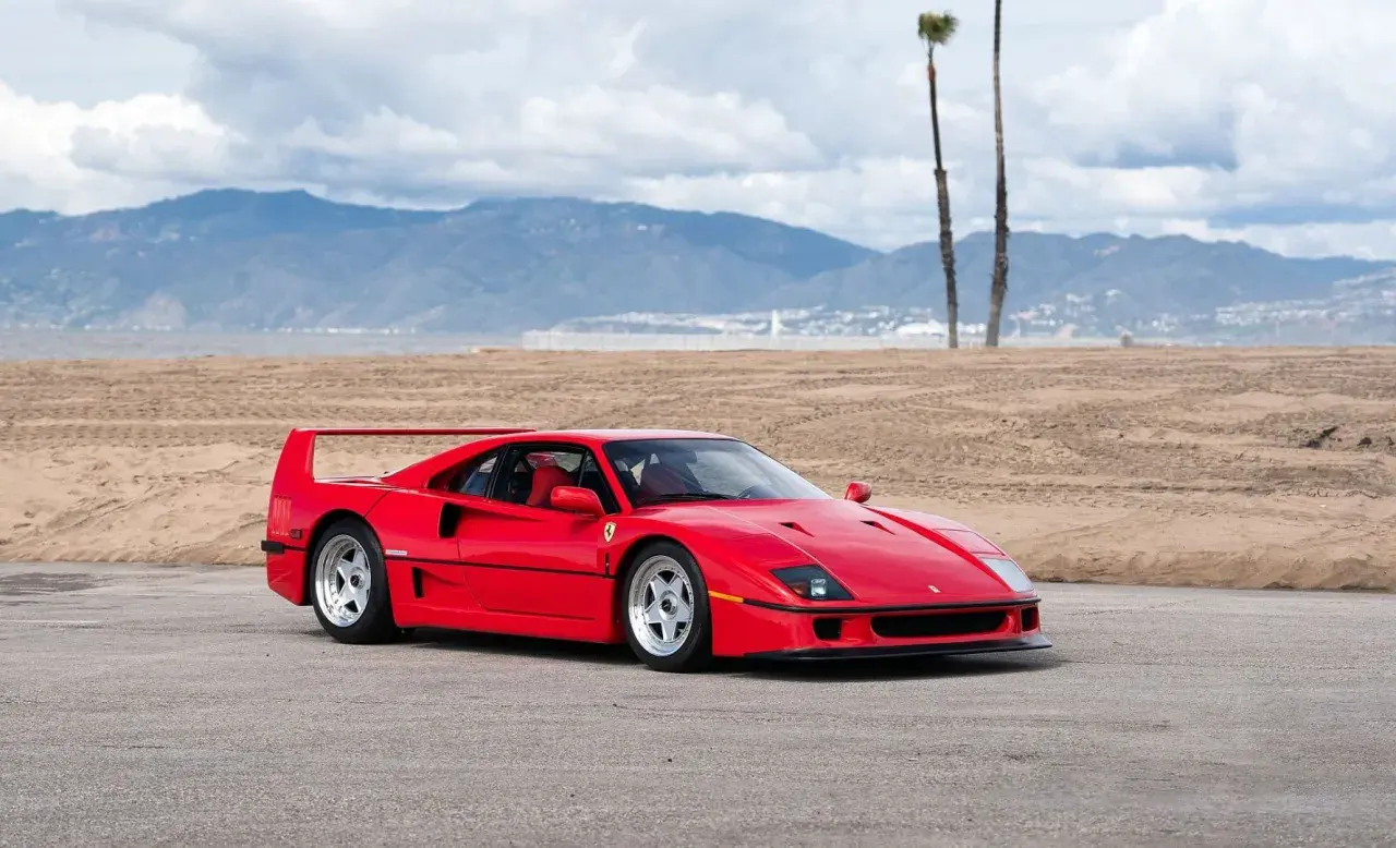 Czerwone Ferrari f40 na tle plaży i gór. Ikona motoryzacji gotowa do jazdy.