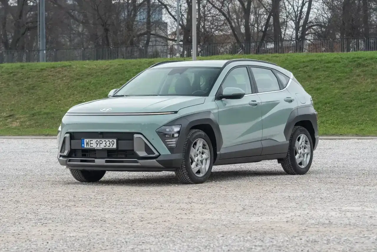 Nowy Hyundai Kona 2025 w kolorze miętowym prezentuje się nowocześnie na tle zieleni i drzew.
