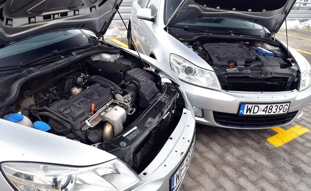 Dwa srebrne samochody z otwartymi maskami, prezentujące swoje silniki. Który wybierzesz: diesel czy benzyna?