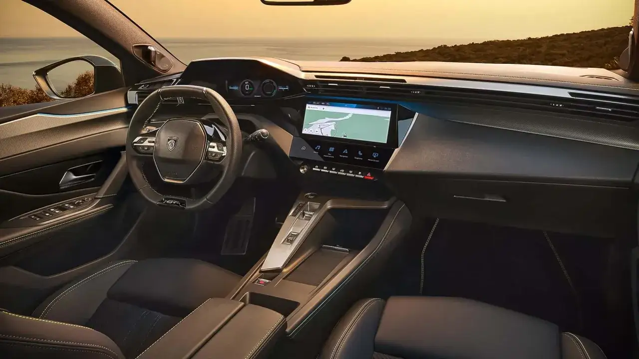 Wnętrze nowego Peugeot 408 z nowoczesnym ekranem nawigacji i cyfrowymi zegarami. Widok na morze przez przednią szybę.