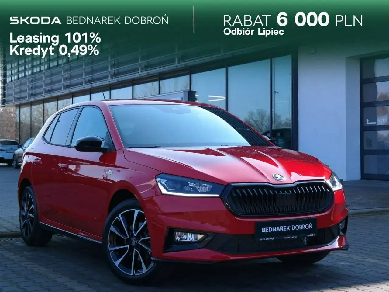 Czerwona Skoda Fabia Monte Carlo z czarnymi akcentami, zaparkowana przed salonem. Oferta leasingu 101% i kredytu 0,49%.