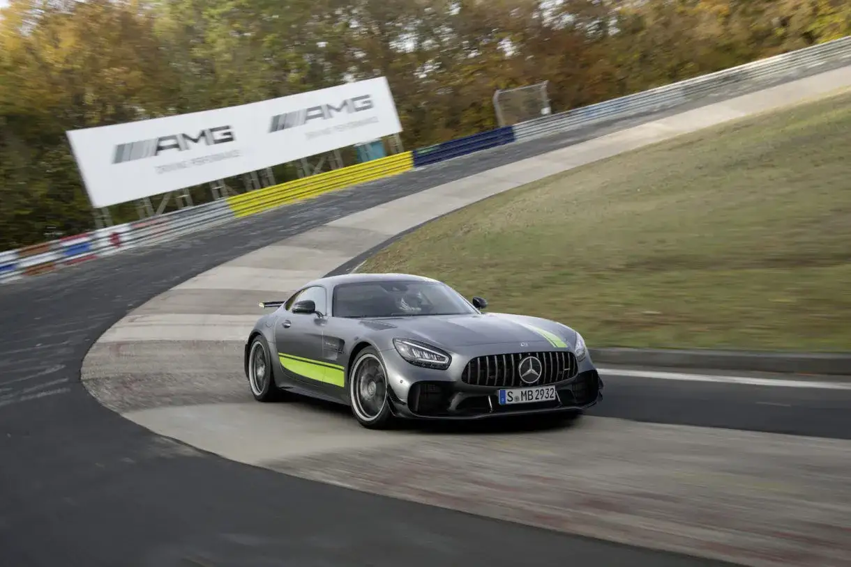 Szary Mercedes-AMG GT R z zielonymi akcentami pędzi po torze wyścigowym. Te sportowe auta to kwintesencja mocy i stylu.
