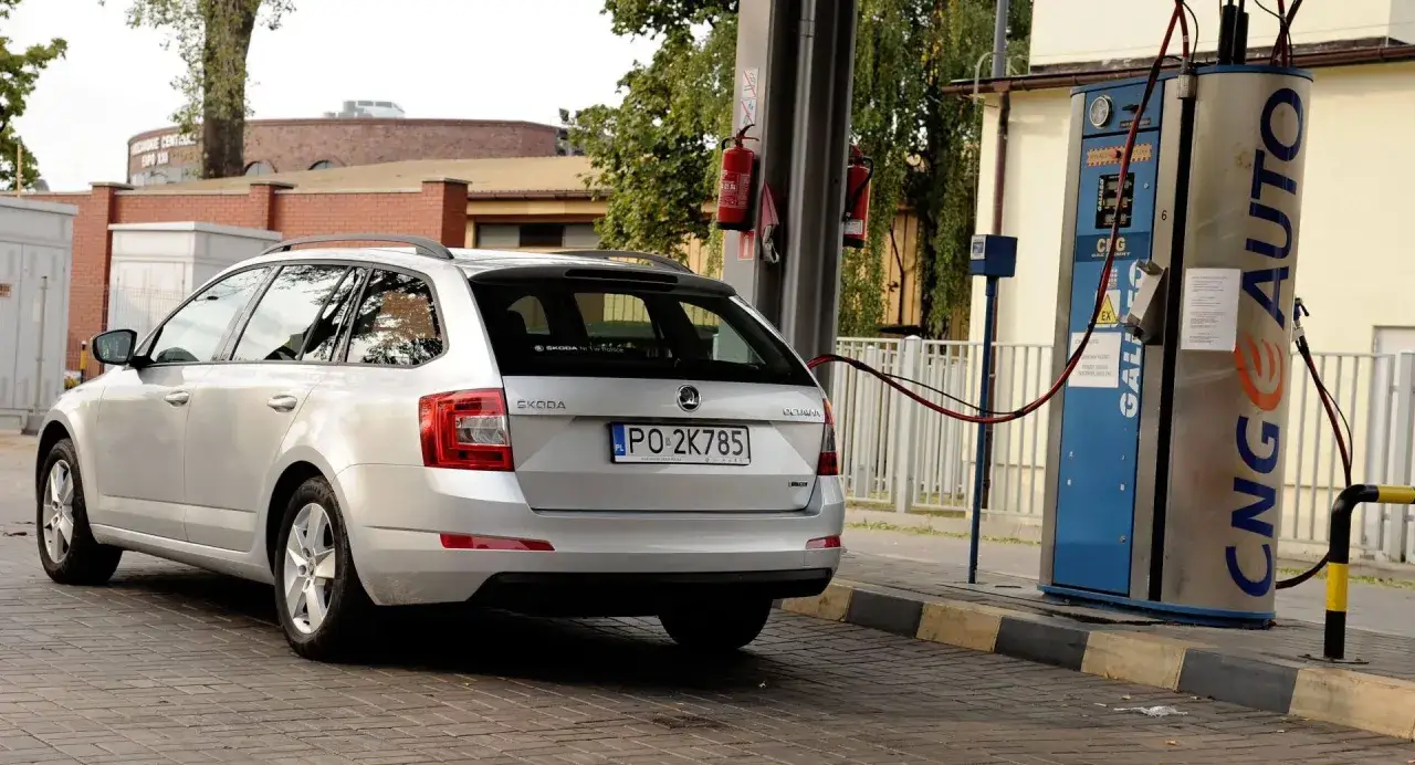 Srebrna Skoda tankuje gaz CNG. Stacja paliw z dystrybutorem CNG AUTO.